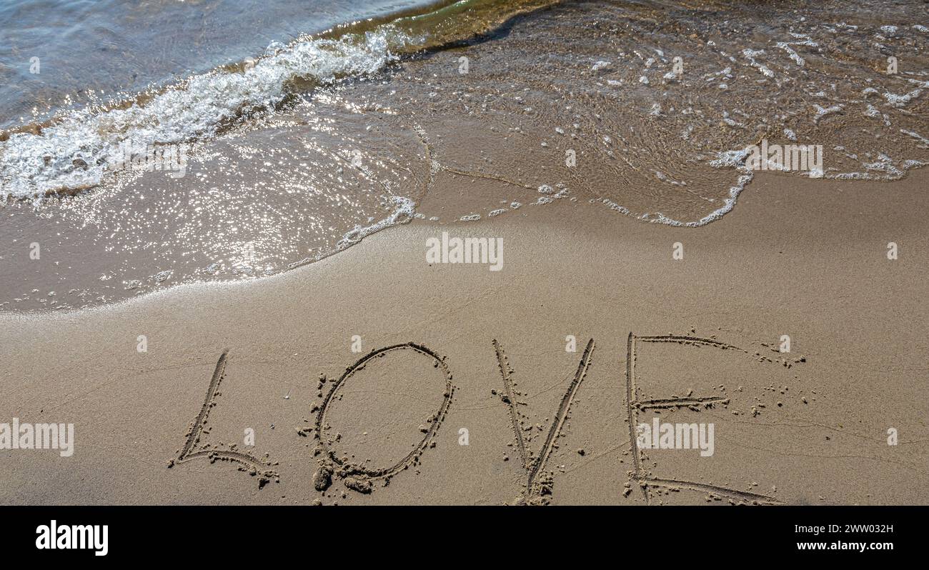 Inscription Love drawn on the sand. Concept of true and honest romantic feelings. spa novel on the sea. Stock Photo