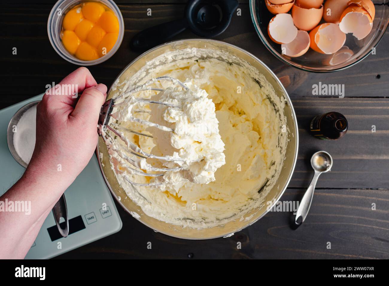Hand Holding a Stand Mixer Whisk Attachment Covered in Buttercream Woman's hand holding a wire