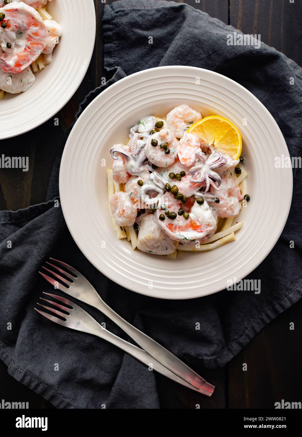 Poached Seafood Salad Served on Celery Root Remoulade: Bowls of shrimp, squid, and scallops with lemon dill sauce served over celeriac remoulade Stock Photo