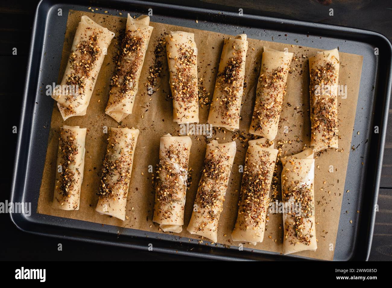 Unbaked Za'atar Spring Rolls on a Sheet Pan: Spring roll appetizers with halloumi cheese and mint topped with za'atar seasoning Stock Photo