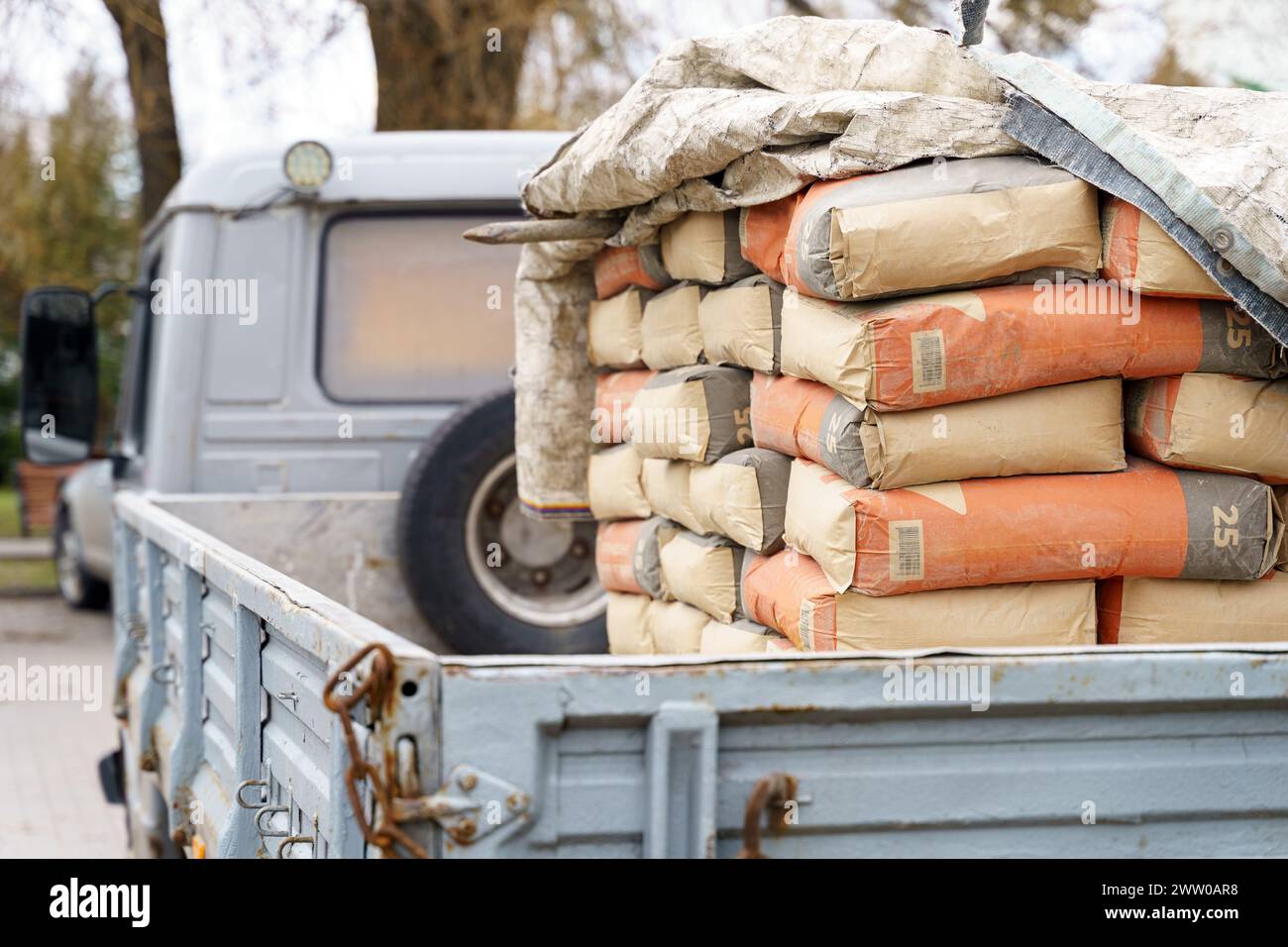 A pickup truck bed is filled with stacked cement bags, indicating ongoing construction work at a site. Stock Photo