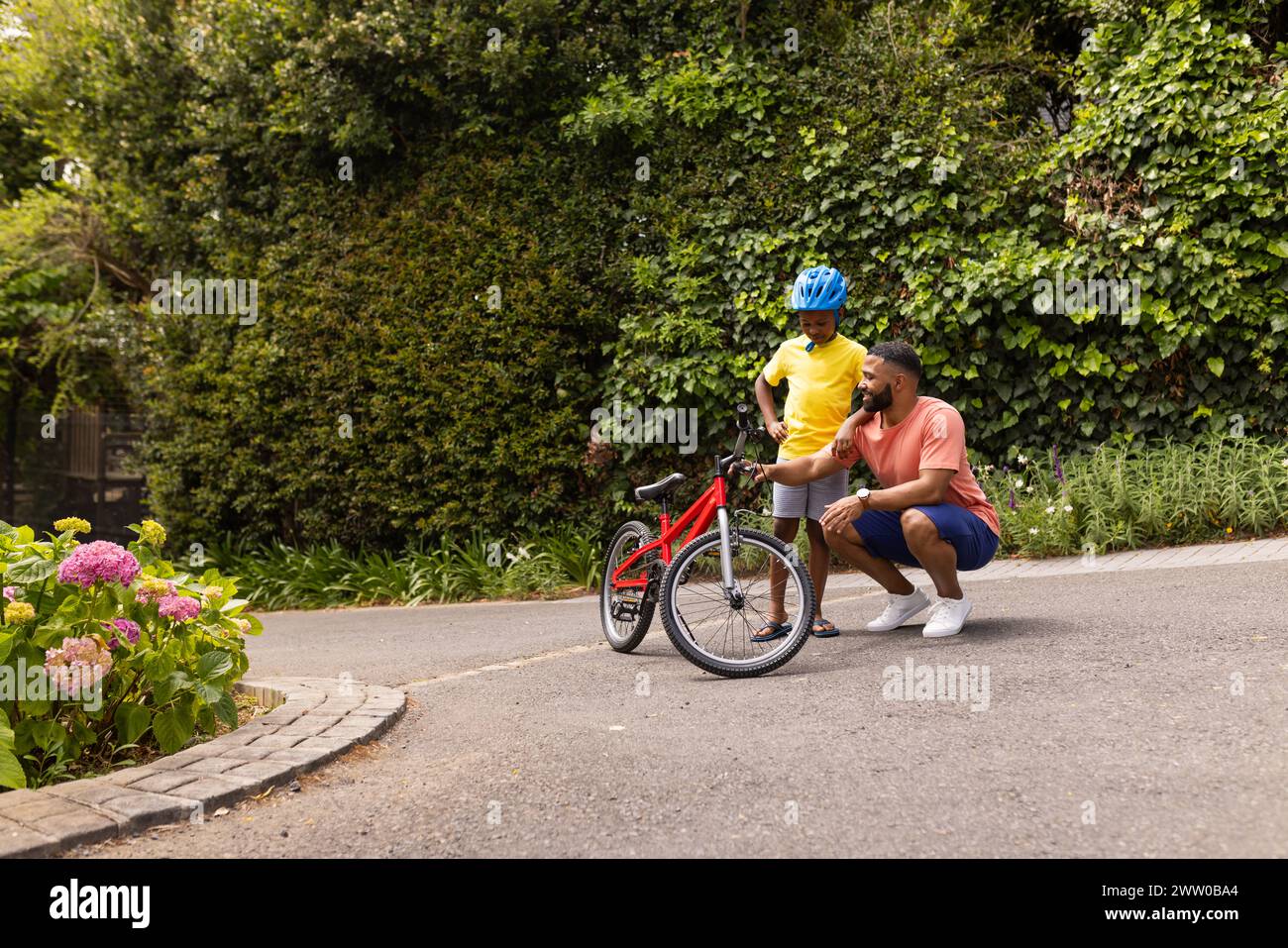 African American father teaches his son to ride a bike Stock Photo