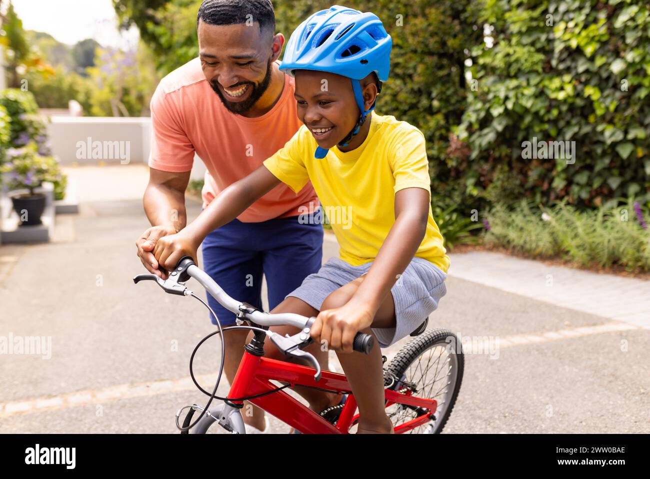 African American father teaches his son to ride a bike Stock Photo