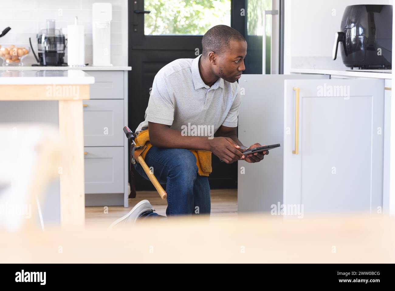 African American plumber fixing sink while using tablet Stock Photo