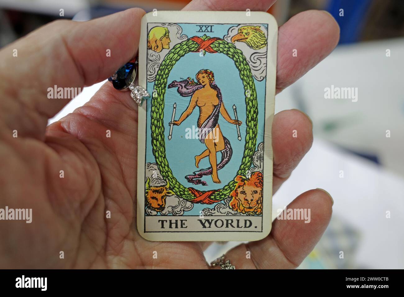 Hand of a fortune teller holding a tarot card in her hand. It's the world.  This card stands for assured success, recompense, voyage, route, emigratio Stock Photo
