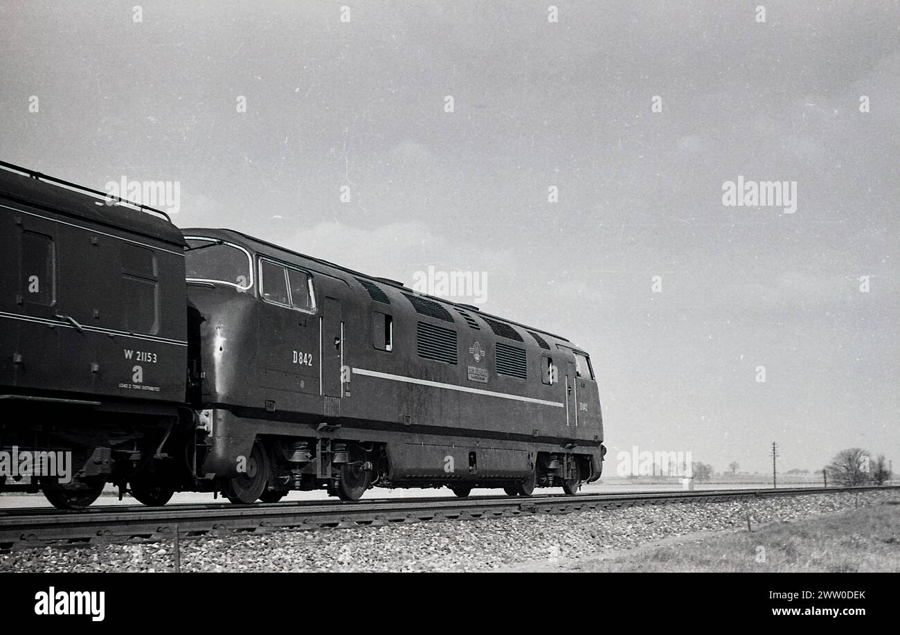 1960s, historical, British Railways diesel locomotive, D842, on rail track, England, UK, pulling carriage W21153. Built in 1960 by North British, the diesel powered Type 4 loco was in service until 1971. Stock Photo
