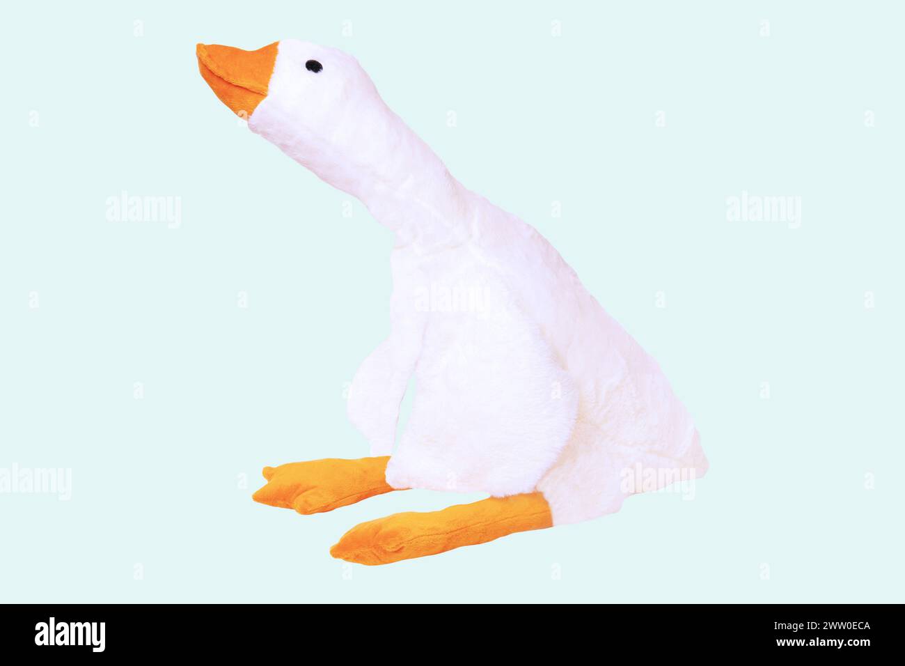 Childrens toy stuffed animals. Soft white plush toy duck for kids isolated on a light blue background. Duck teddy toy. White duck for playing. Stock Photo