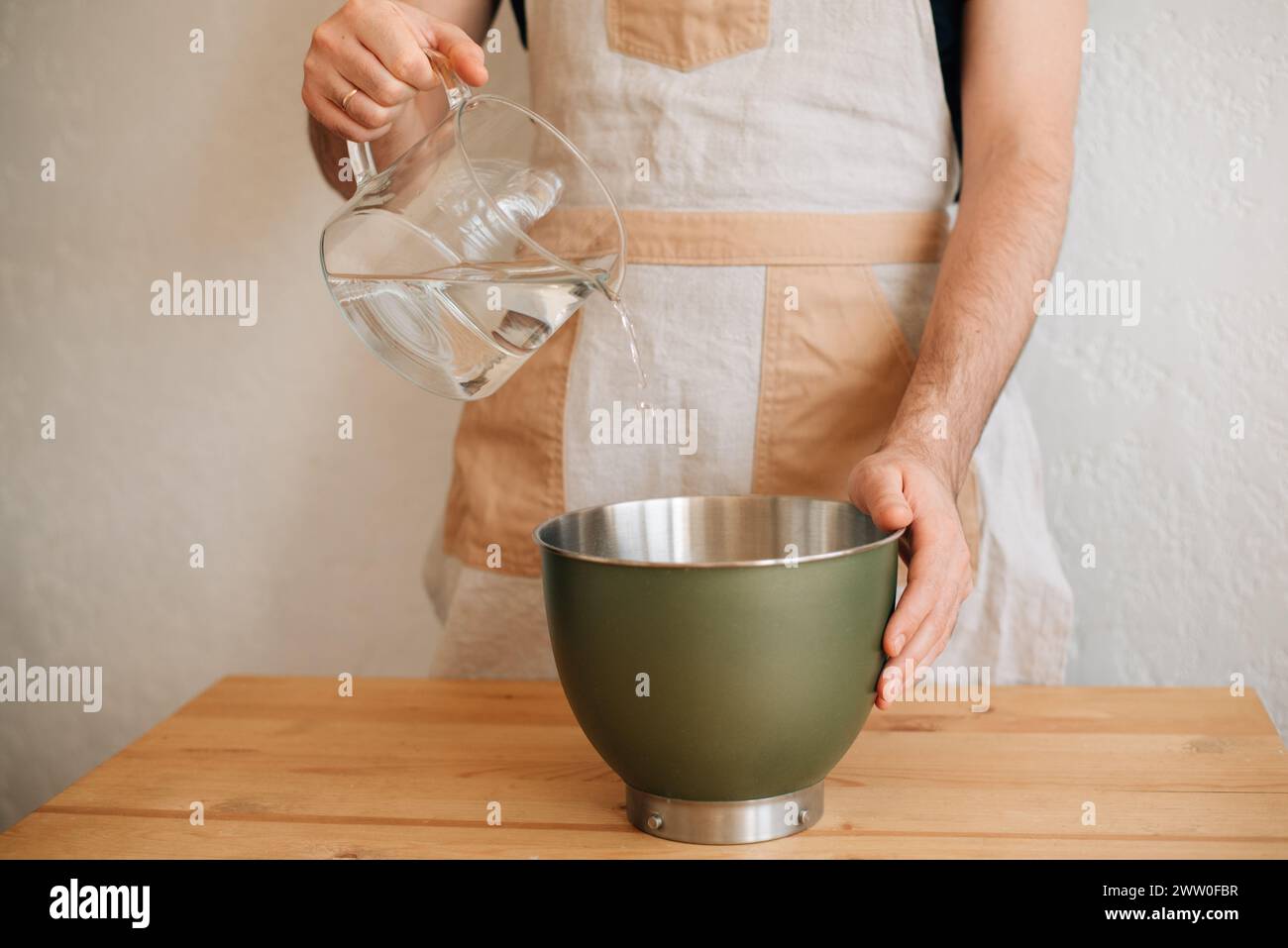 male baker pours water into a bowl of flour. High quality photo Stock Photo