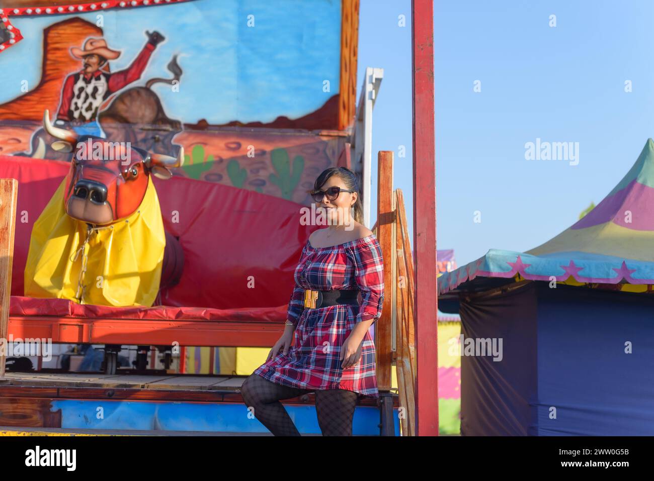 Portrait of a woman next to a mechanical bull at a fair in Mexico. Stock Photo