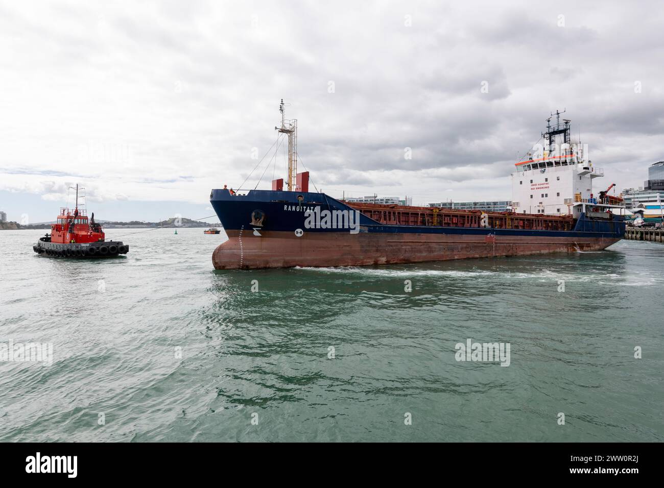 Two tug boats assist the Cargo ship Rangitata to get off the dock at Auckland. Stock Photo