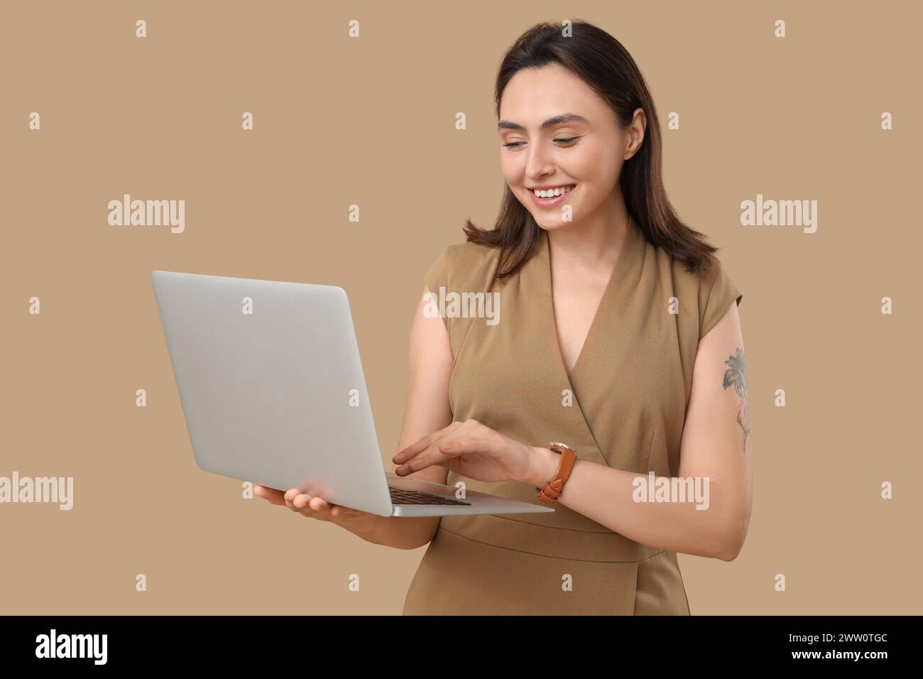 Pretty young woman with laptop on beige background Stock Photo - Alamy