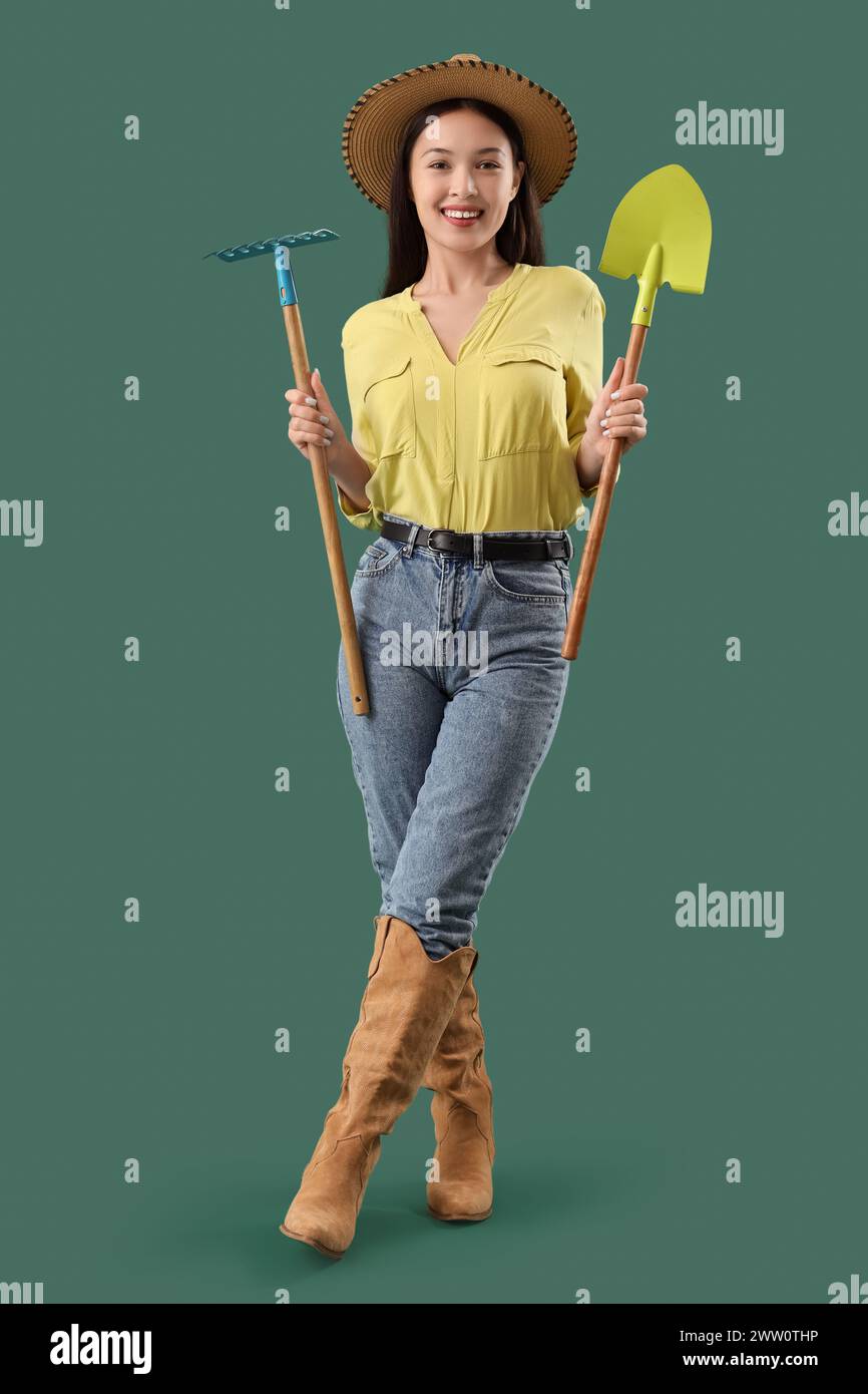 Female Asian farmer with rake and shovel on green background Stock ...