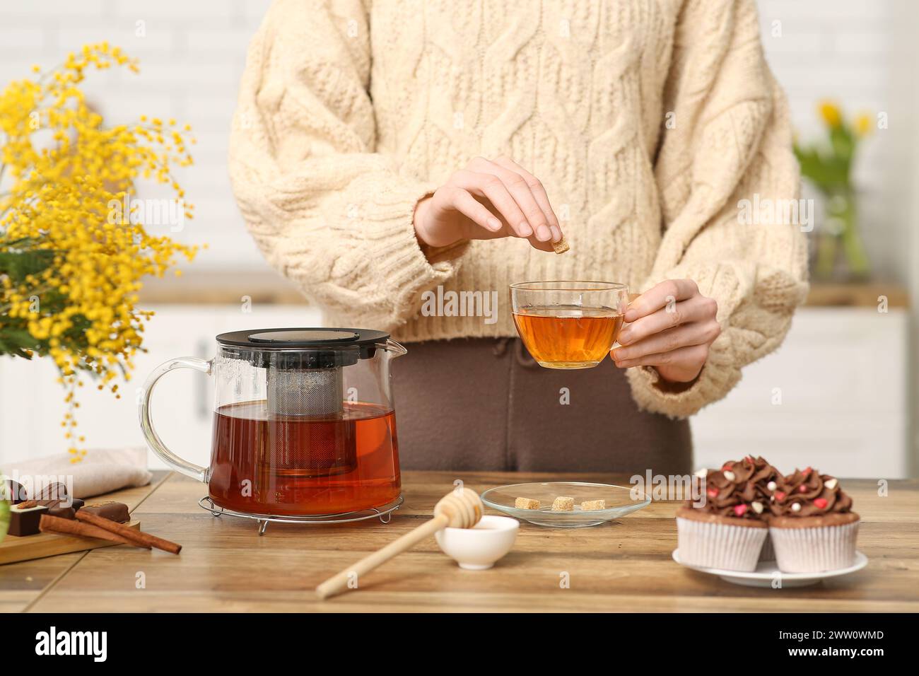 Young woman adding sugar into cup of tea in kitchen Stock Photo - Alamy