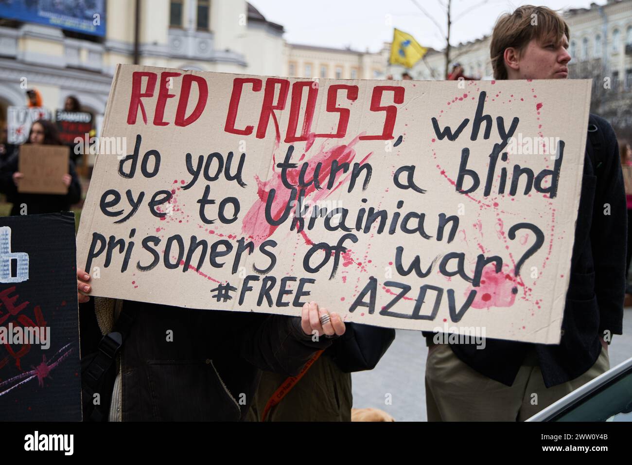 Activist holds a sign 'Red Cross, Why Do You Turn A Blind Eye To Ukrainian Prisoners Of War? Free Azov' on a public protest. Kyiv - 17 March,2024 Stock Photo