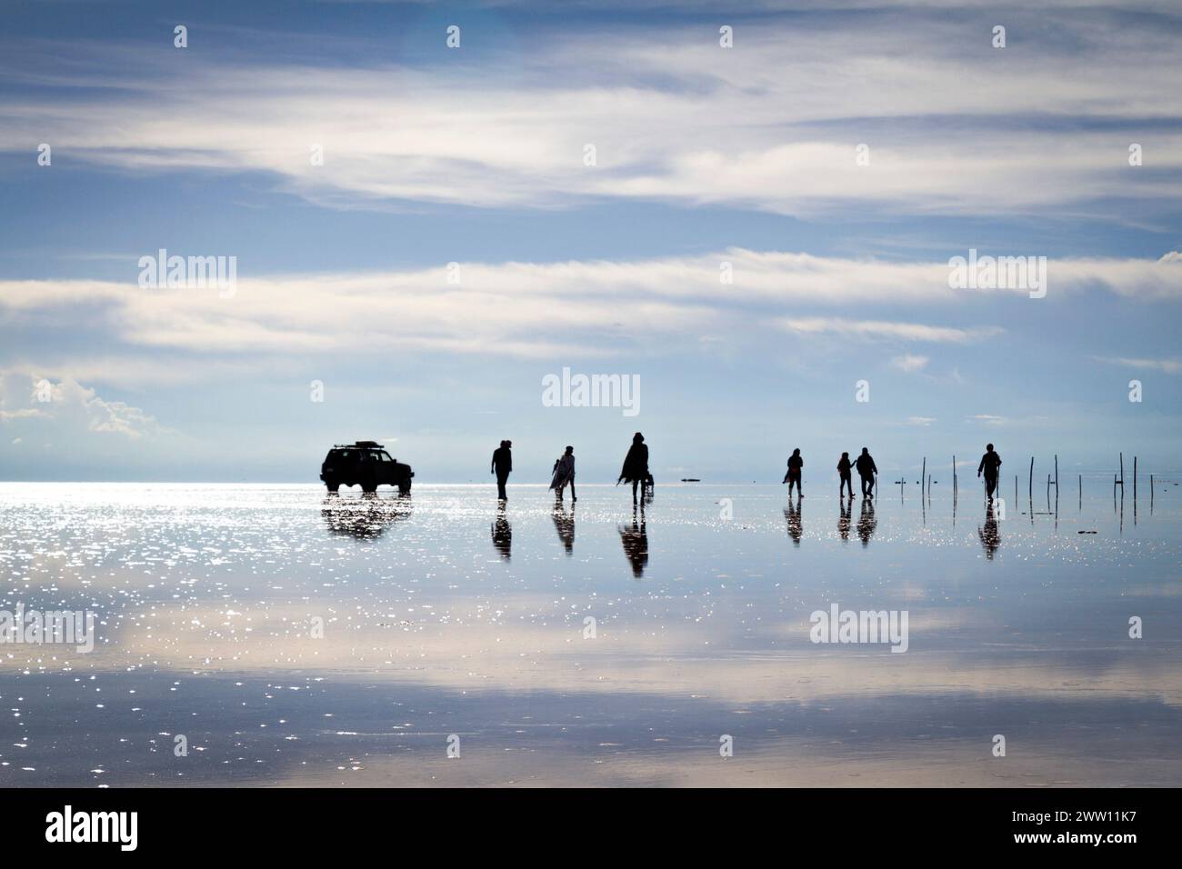 Silueta de turistas en salar de Uyuni, efecto reflejo Stock Photo