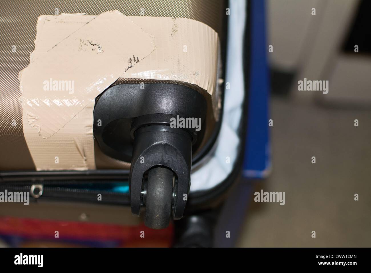 Suitcase with wheel and corner repaired with adhesive tape, showing a temporary solution. Stock Photo