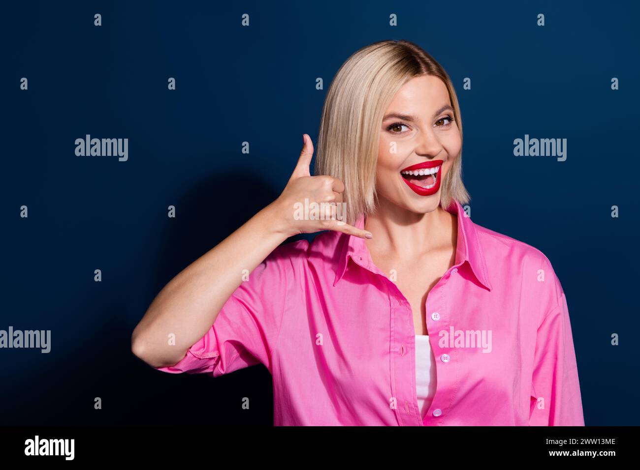 Photo of funky pretty girl with bob hairdo dressed pink shirt hold hand near ear say call her isolated on dark blue color background Stock Photo