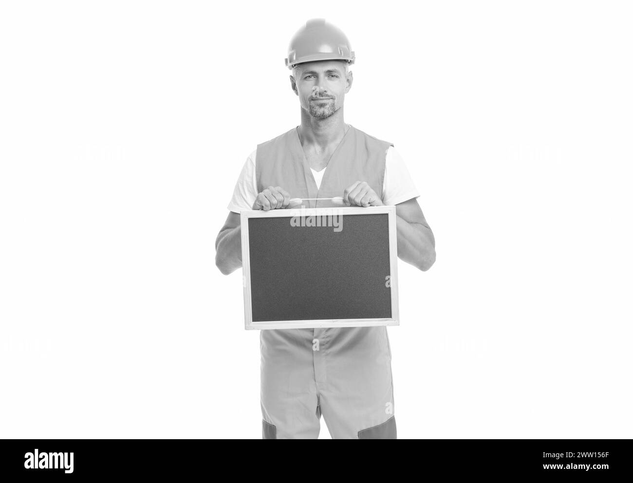 photo of cheerful builder show advertisement holding blackboard. Stock Photo