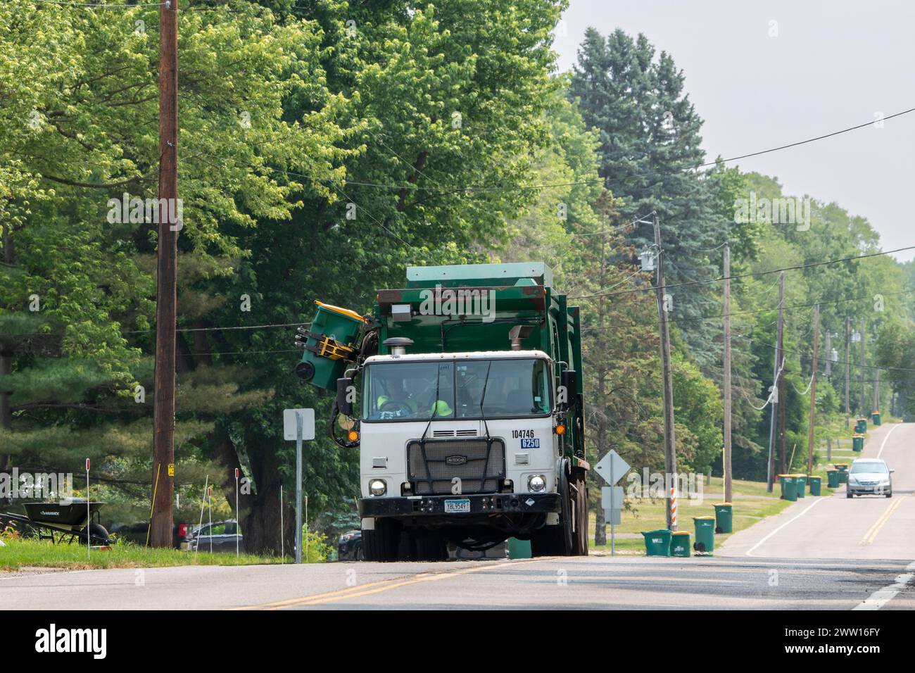 Vadnais Heights, Minnesota. Garbage truck hauler picking up the trash bins lined up alongside the road. Stock Photo