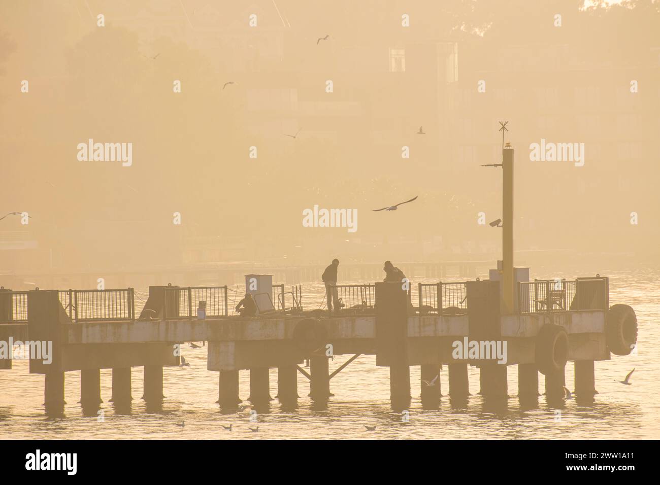 A hazy sunset in Istanbul on a pier as workers finish their day Stock Photo