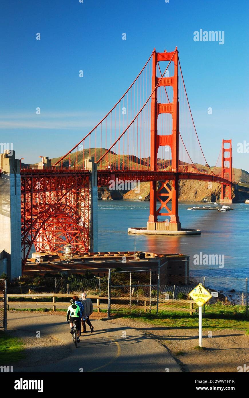 Two bicycle riders ridge their bikes downhill towards the Golden Gate Bridge in San Francisco Stock Photo