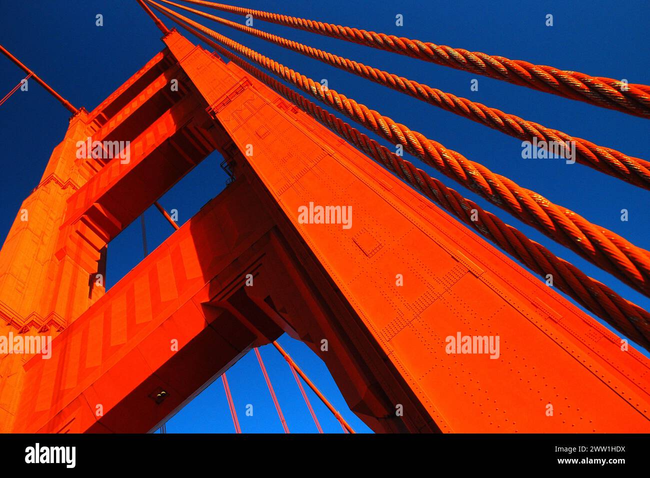 The orange anchor and the cables of the of the Golden Gate Bridge in San Francisco rise to the sky on a sunny day Stock Photo