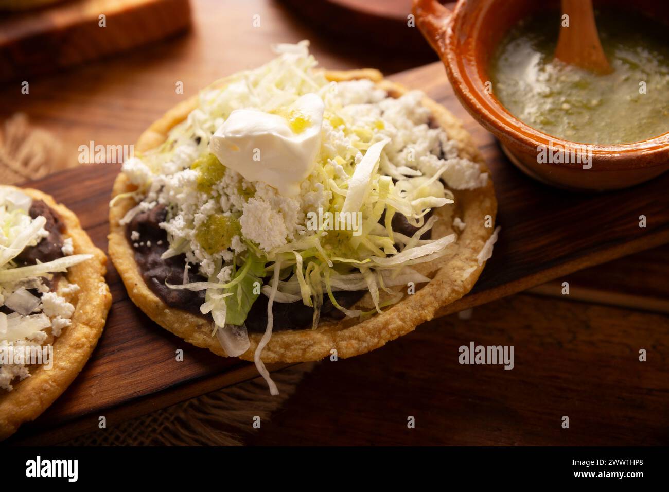 Sope. Traditional homemade Mexican food prepared with flattened and pinched on the border fried corn dough covered with refried beans, green or red sa Stock Photo