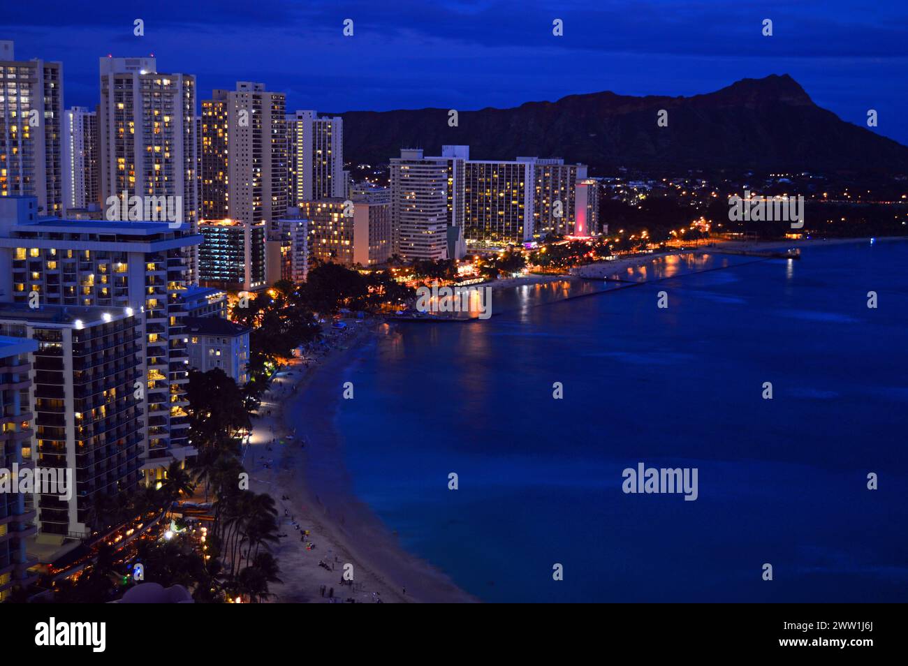 The lights of the hotels along the shore of Waikiki Beach in Hawaii are illuminated at night as seen in an aerial view Stock Photo