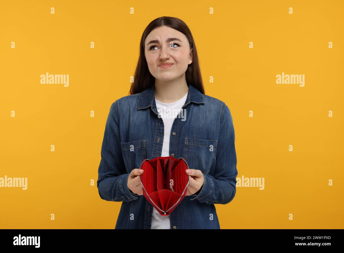 Sad woman showing empty wallet on orange background Stock Photo - Alamy