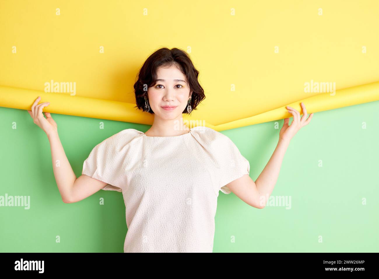 Asian woman holding up yellow and green paper Stock Photo