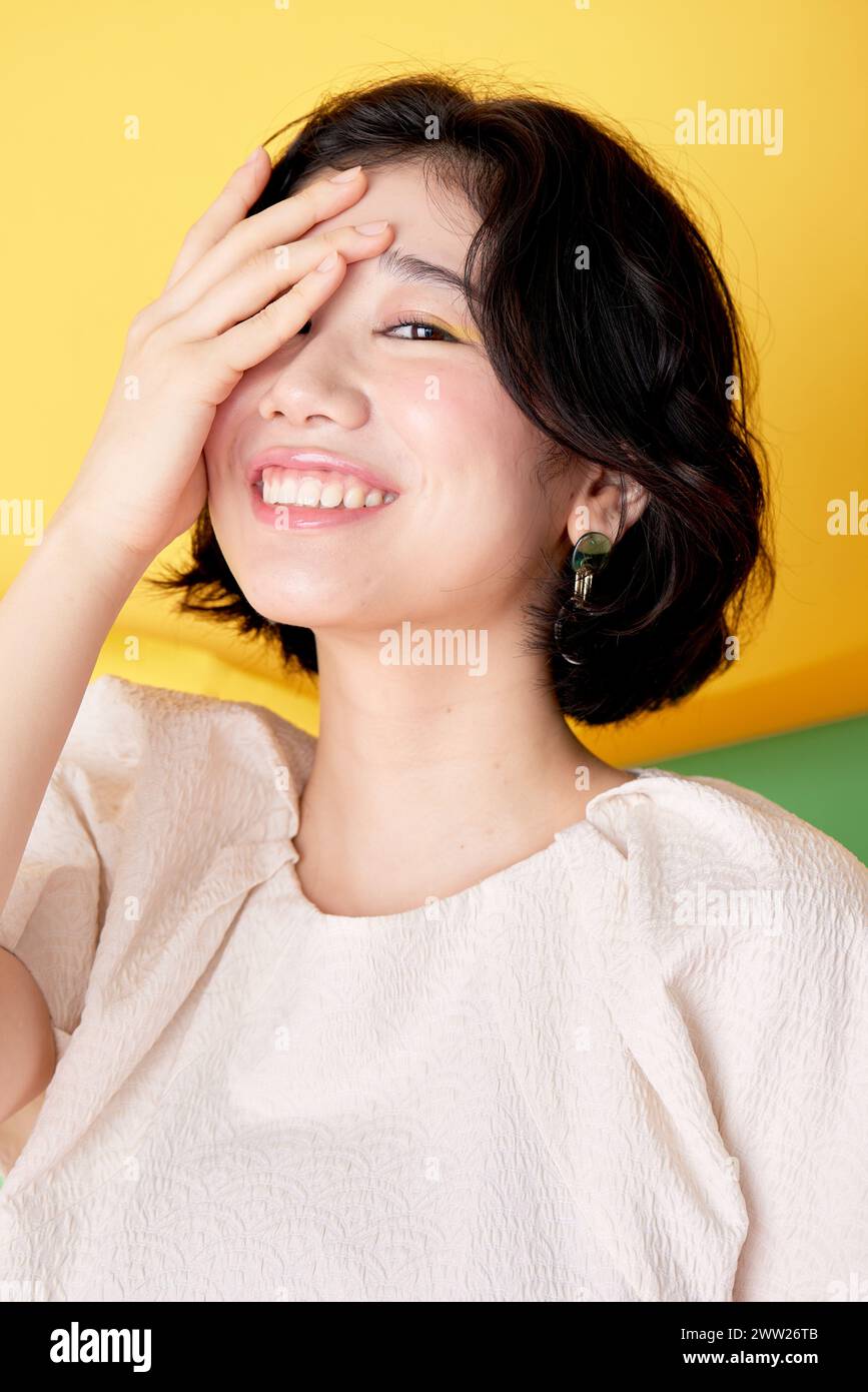 A woman smiling and covering her eyes with her hand Stock Photo - Alamy