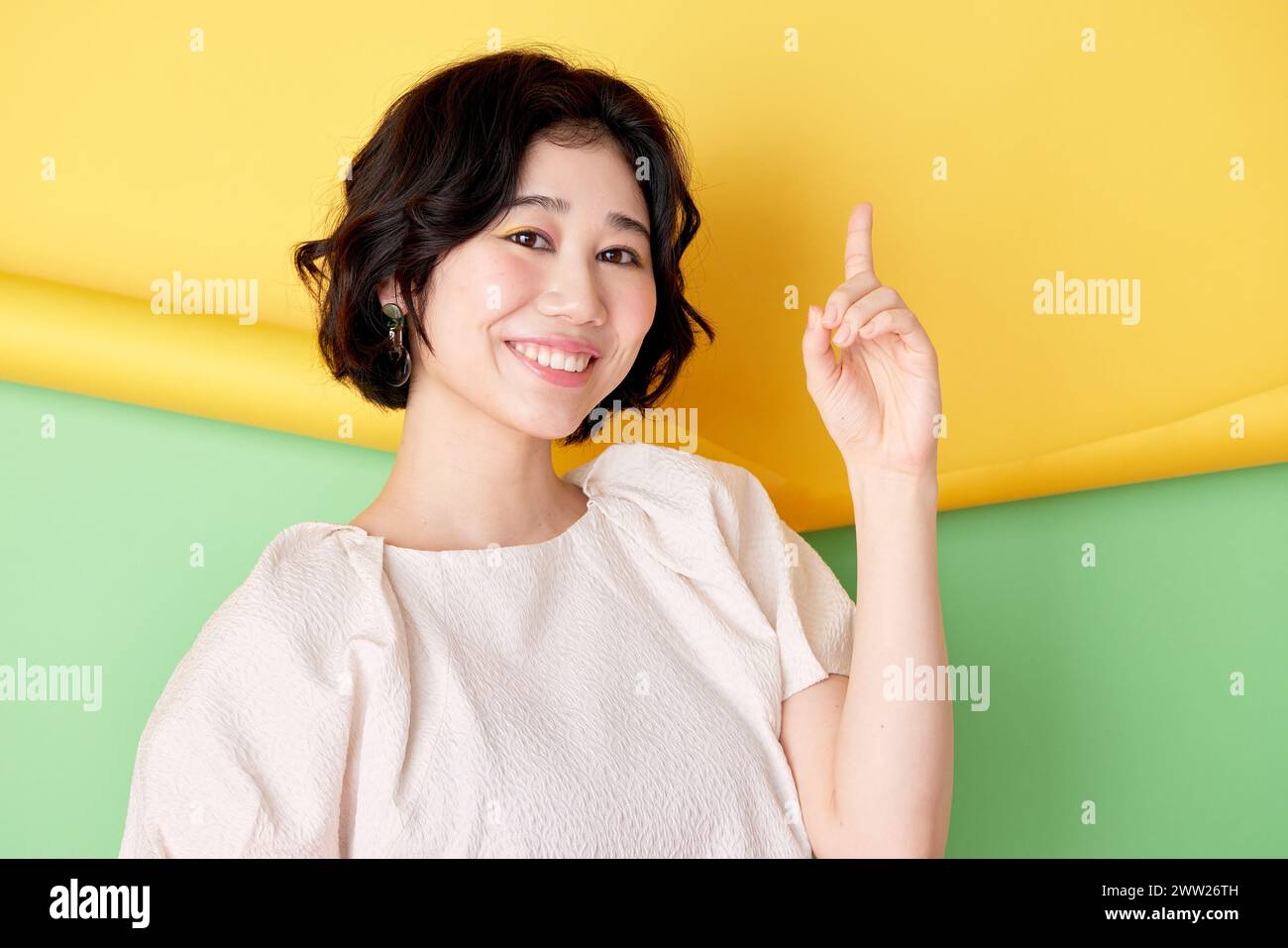 Asian woman pointing finger up on colorful background Stock Photo
