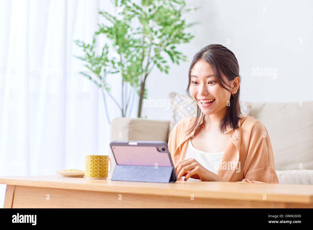 Asian woman using tablet computer in living room Stock Photo