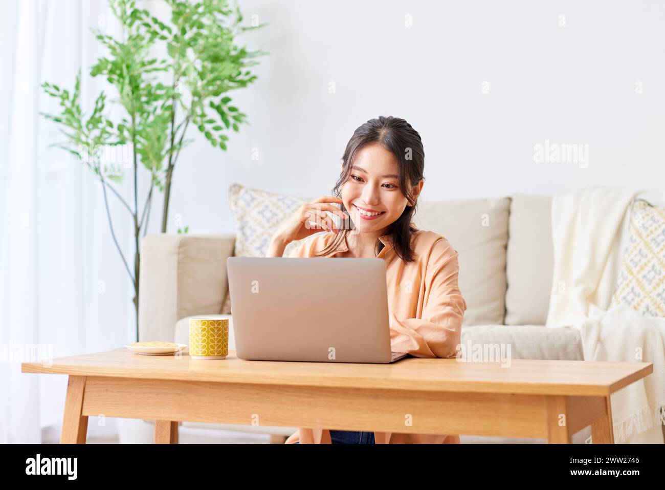 Asian woman using laptop in living room Stock Photo