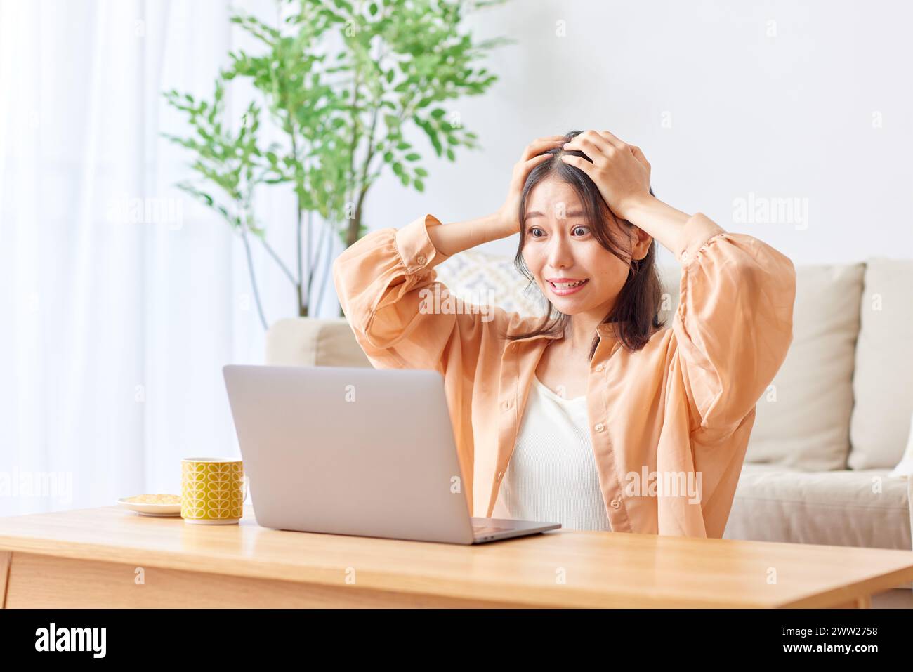 A woman sitting at a table with her laptop Stock Photo