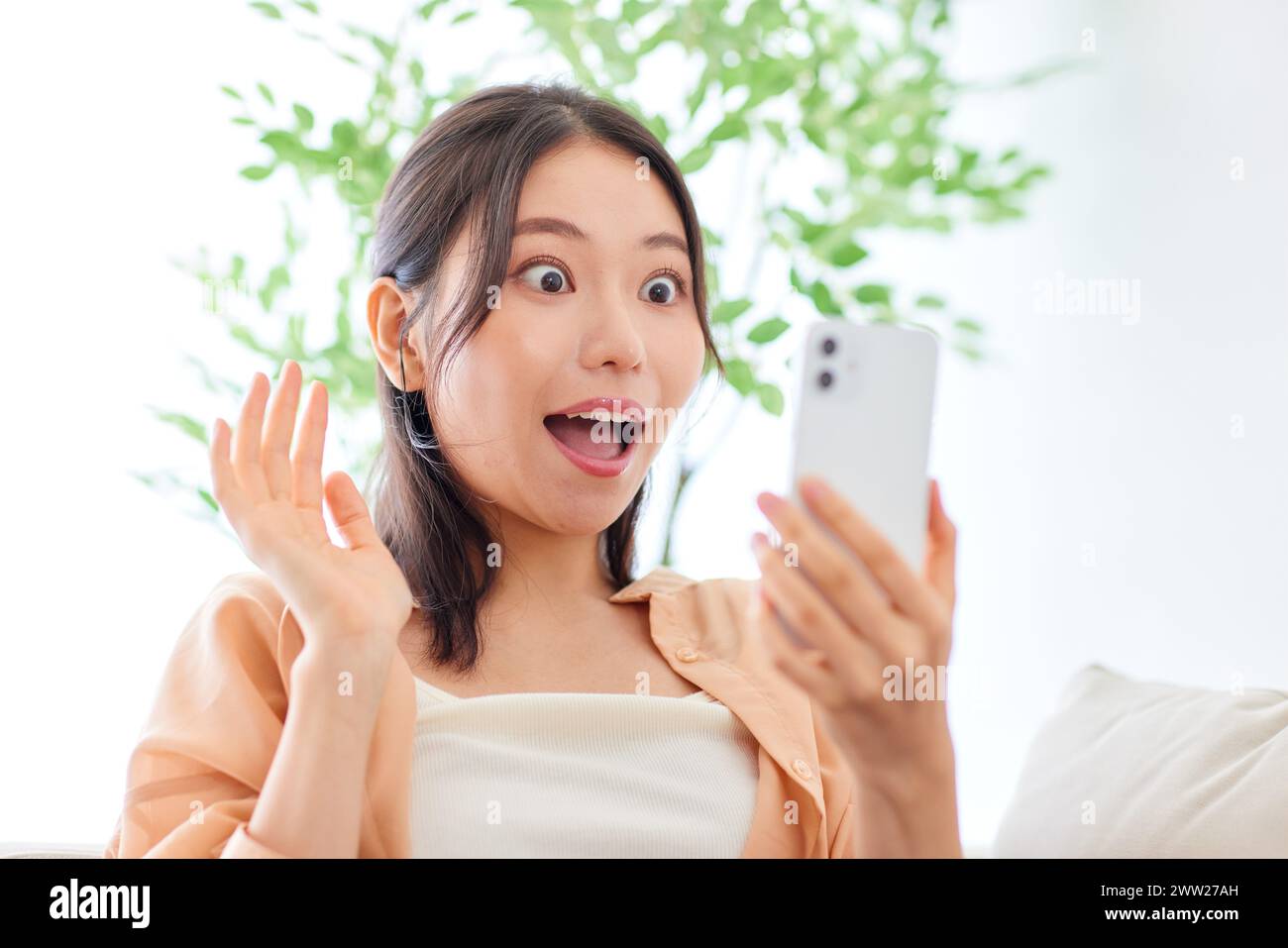 A woman holding a cell phone and looking surprised Stock Photo