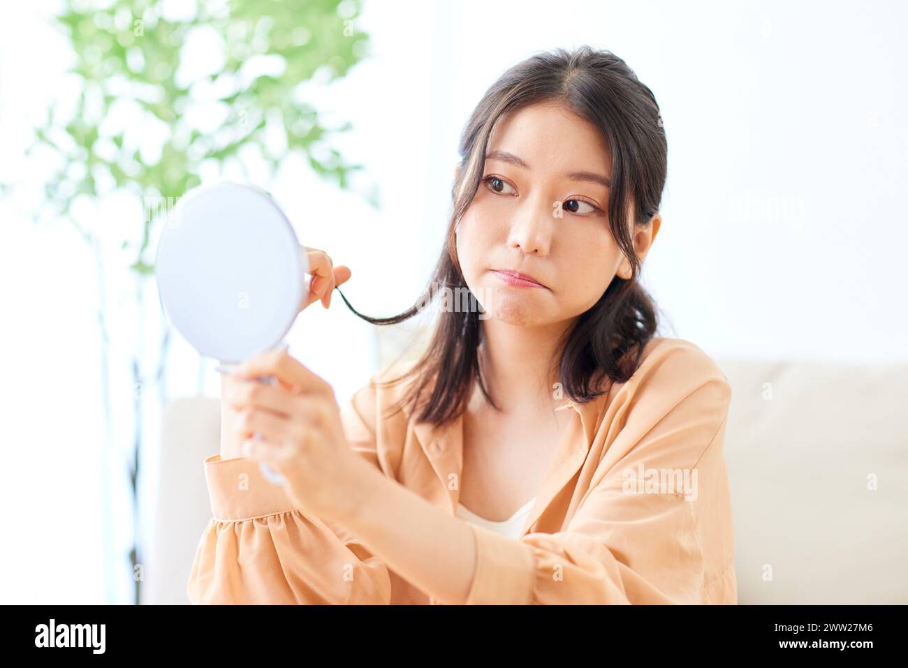 A woman looking at her reflection in a mirror Stock Photo