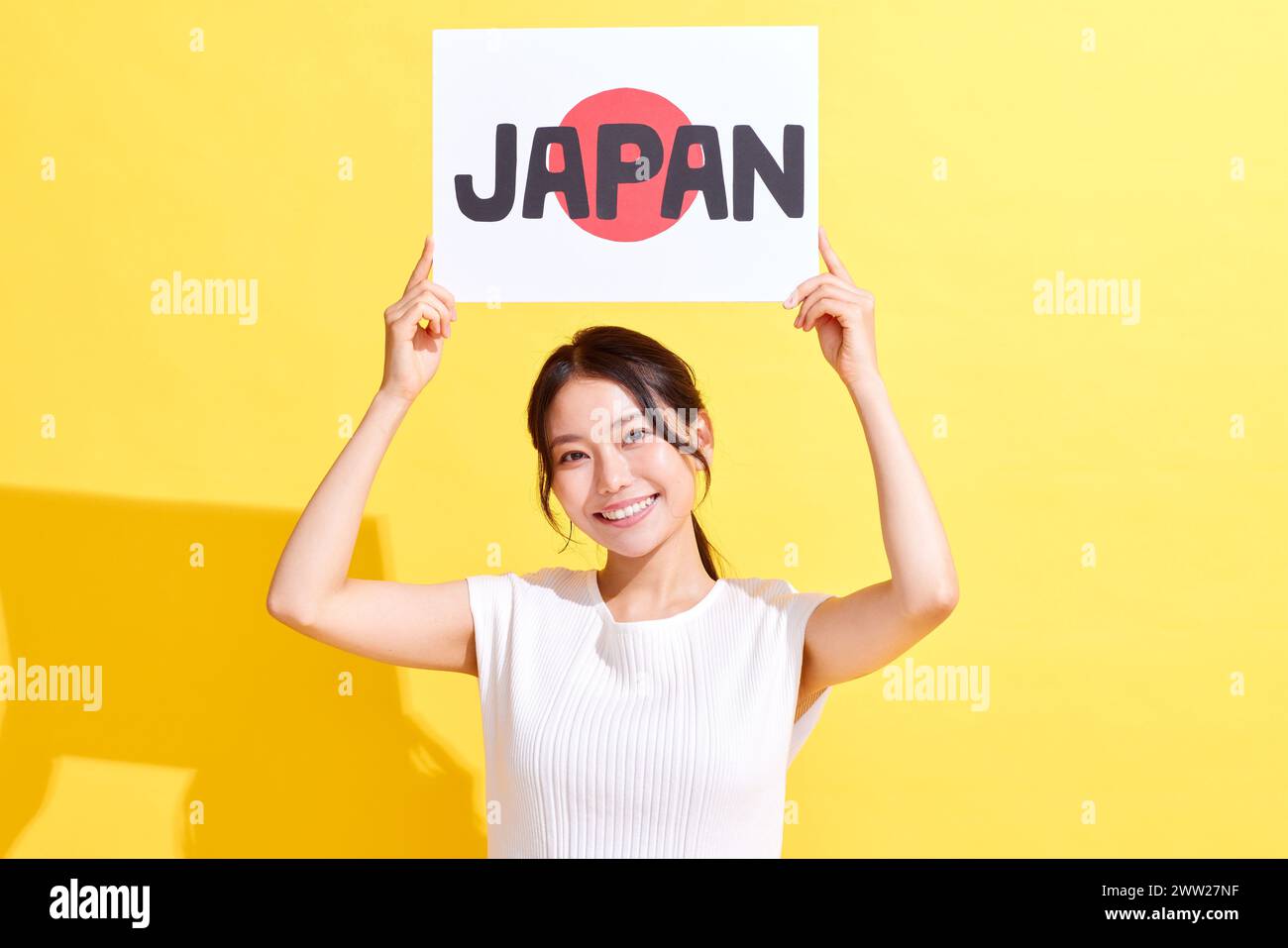 A woman holding up a sign with the word Japan Stock Photo
