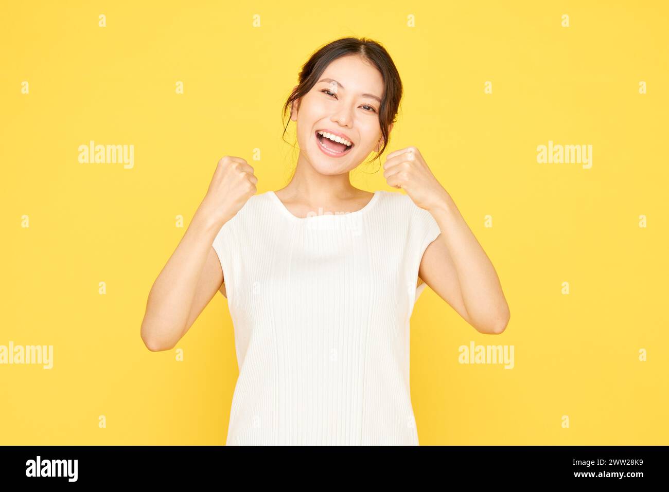 A woman in a white shirt raising her fists Stock Photo