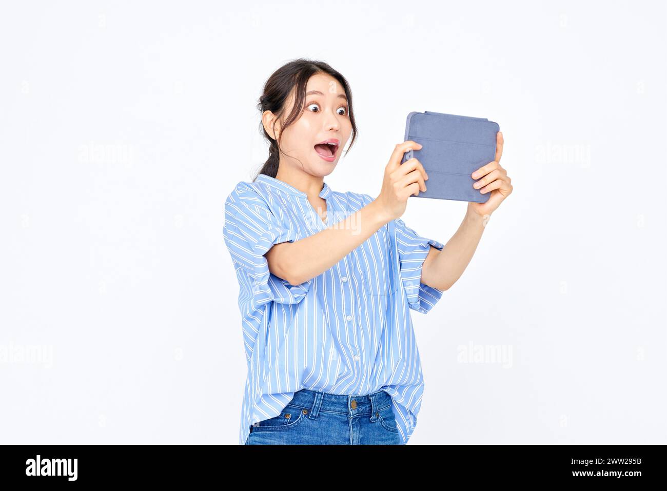 A woman holding a tablet and looking surprised Stock Photo