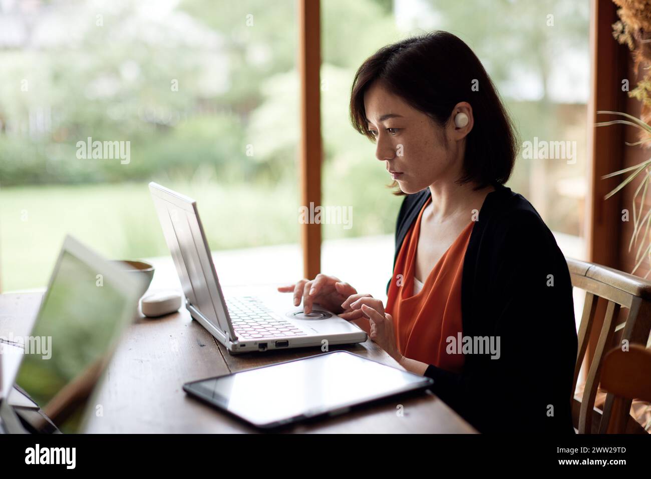A woman sitting at a table with a laptop Stock Photo