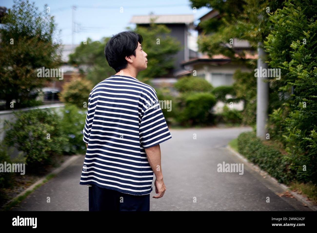 A man wearing a striped shirt stands on a street Stock Photo