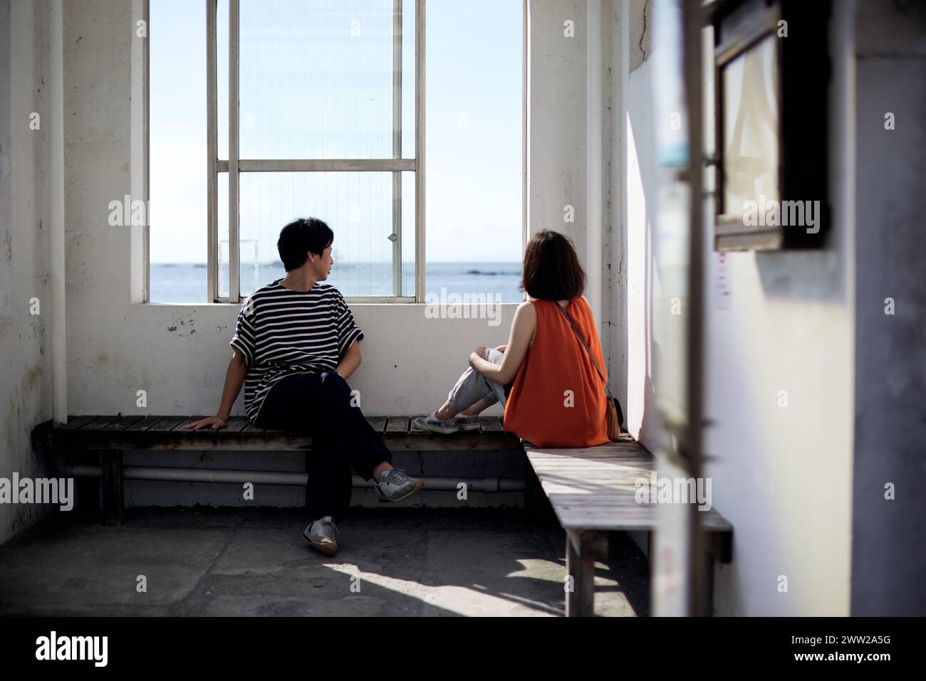 A couple sitting on a bench looking out at the ocean Stock Photo - Alamy