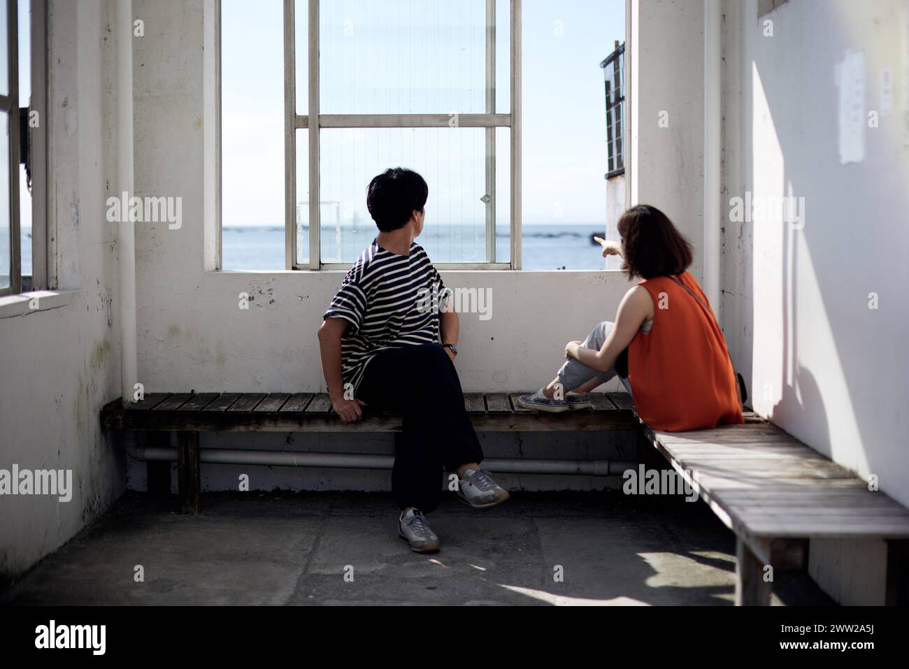A couple sitting on a bench looking out at the ocean Stock Photo - Alamy