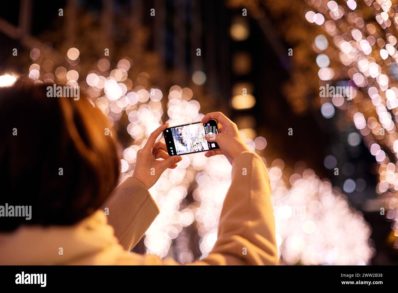 A woman taking a photo of a city street at night Stock Photo