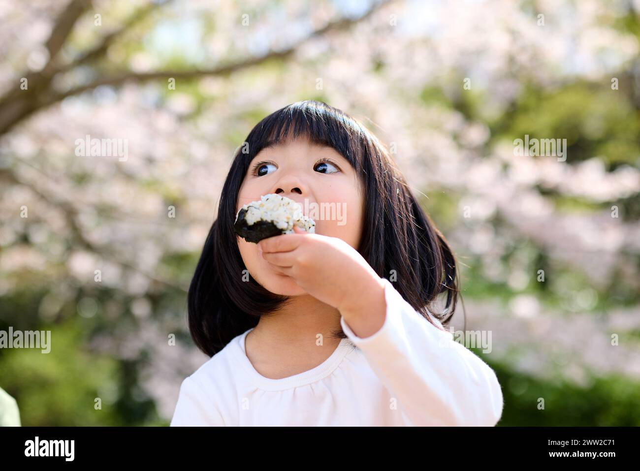 A little girl eating a rice ball Stock Photo