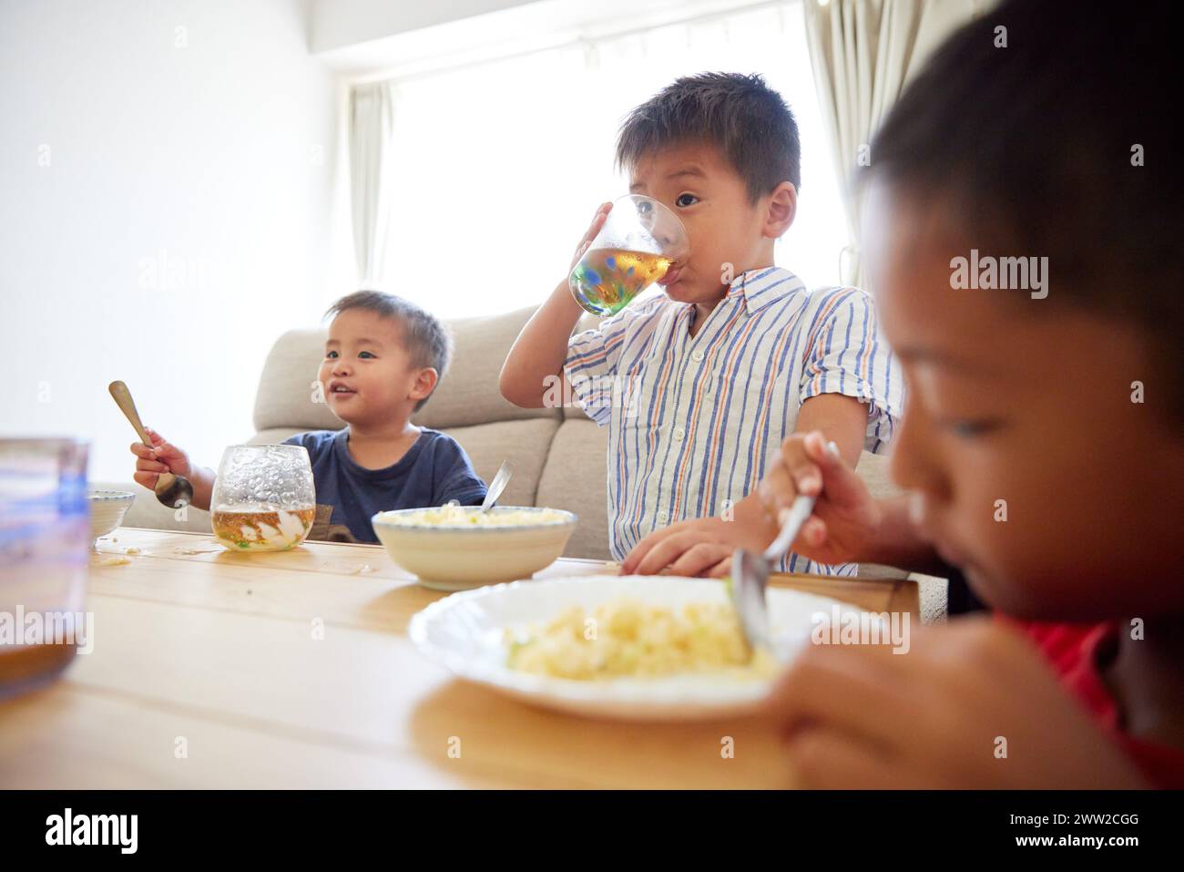 Three children eating food at a table Stock Photo