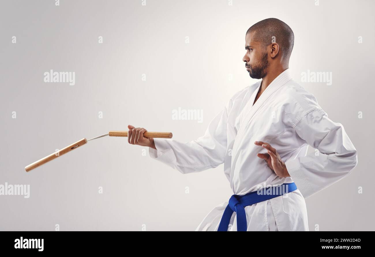 Nunchucks, karate and man in martial arts fight with weapon in training for defence in white