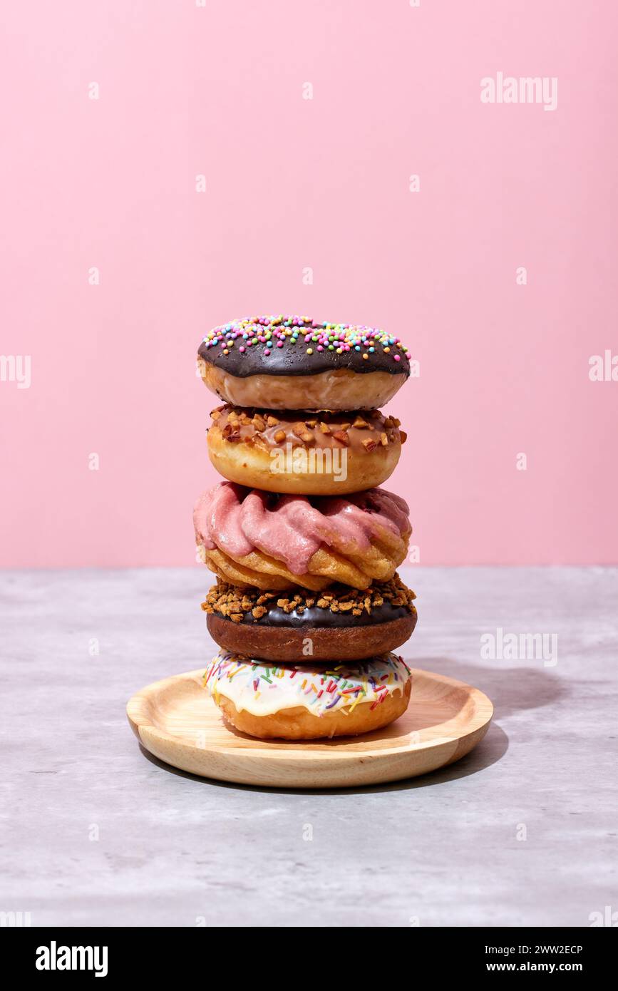 A stack of donuts on a plate with pink background Stock Photo