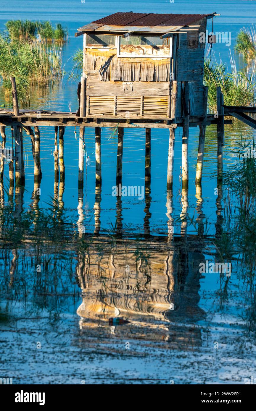 Tranquil waters. Cabin fishing hut amidst reeds.  Light and shadow. Stock Photo